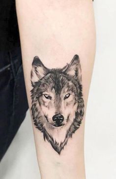 a black and white wolf tattoo on the arm