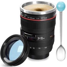 a camera lens mug with a spoon next to it