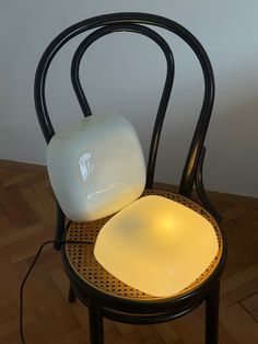 a lamp sitting on top of a black chair next to a white light bulb in the shape of a square