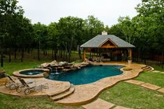 a backyard with a swimming pool, patio and gazebo in the middle of it