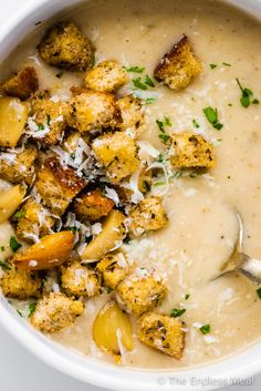 a white bowl filled with soup covered in cheese