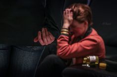 a woman holding her hands to her face while sitting on a couch next to a man