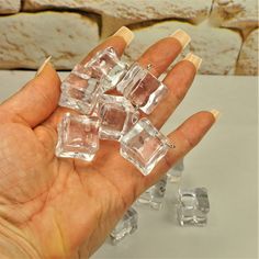 a hand holding several clear cubes of ice