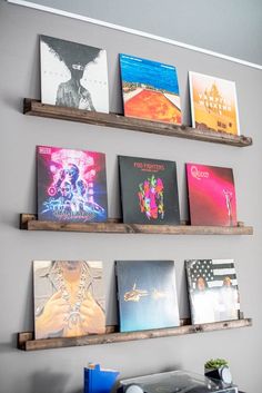 some books are hanging on the wall in front of two shelves that have posters on them