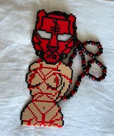 a beaded iron man keychain is laying on a white sheet with red beads