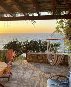 a hammock hanging from the side of a stone wall next to an ocean