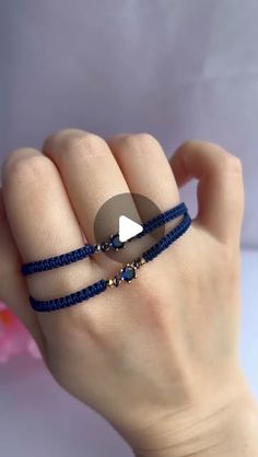 a woman's hand with two blue bracelets and a white triangle on it