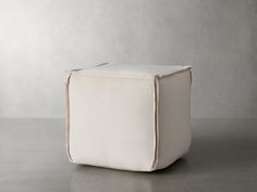 a white square ottoman sitting on top of a floor