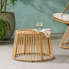 a wicker table with a wine glass on it next to a potted plant