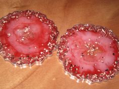 two red dishes with sprinkles on them sitting on a wooden table next to each other