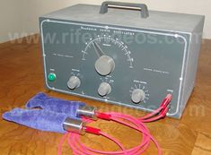 an old radio and some wires on a wooden table with a purple towel next to it