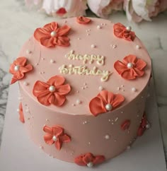 a pink birthday cake with flowers on it