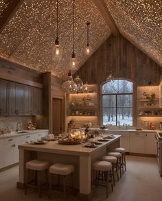 a kitchen filled with lots of counter top space and lights hanging from the ceiling above it