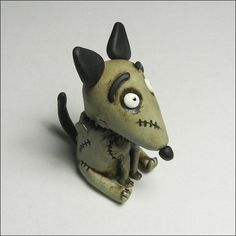 a small figurine of a dog with big eyes sitting on a white surface