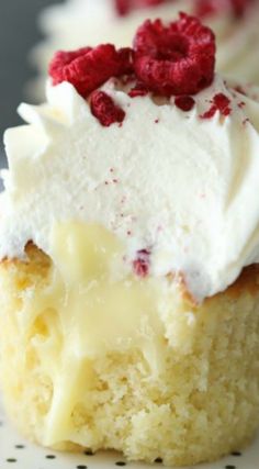 a piece of cake with white frosting and raspberries on top