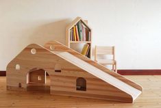 a child's play house made out of wood with a slide on the floor