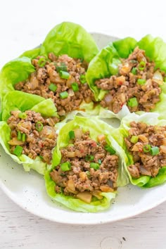 lettuce wraps filled with minced meat and green onions on a white plate