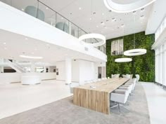 a conference room with green walls and white chairs around a wooden table in front of two circular chandeliers hanging from the ceiling