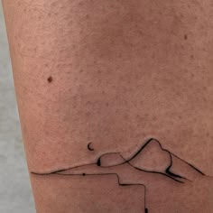 a tattoo on the leg of a person with a mountain and moon in the background