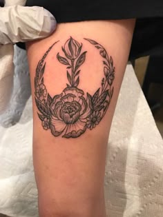 a black and white photo of a woman's thigh with a flower tattoo on it