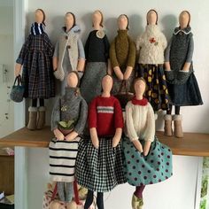 a group of dolls sitting on top of a wooden shelf