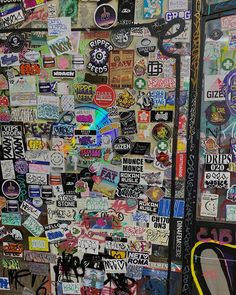 a wall covered in lots of stickers and graffiti