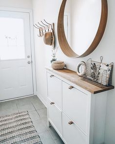 there is a mirror on the wall above a dresser in this room with white walls and flooring