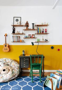 a child's room with yellow walls and blue rugs, bookshelves on the wall