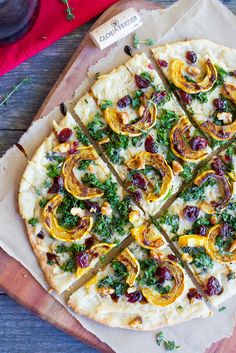 a pizza with cheese, olives and other toppings on a wooden cutting board