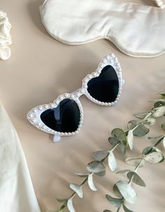 two heart shaped sunglasses sitting on top of a white sheet