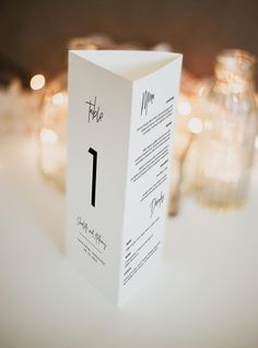 the table numbers are placed on top of each other in front of candles and glass vases