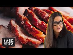 a woman with glasses standing in front of sliced meat