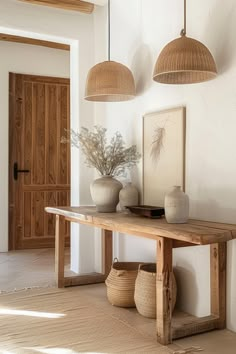 two vases are sitting on a table in the middle of a room with white walls