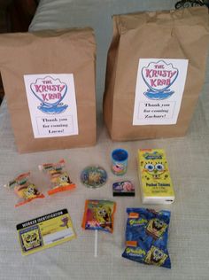 two brown bags filled with snacks and candy on top of a white tablecloth covered bed