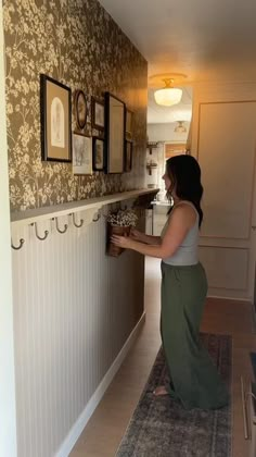 a woman standing in front of a wall with pictures on it