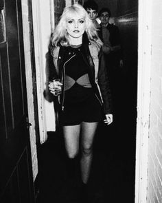 a black and white photo of a woman in a short skirt walking down a hallway