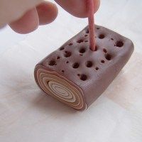 a person holding a toothbrush in front of an ice cream sandwich shaped like a roll