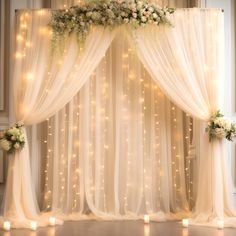 an image of a wedding stage setting with flowers and lights on the curtained wall