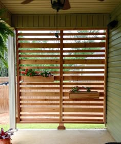 an outdoor patio with wooden slats and plants on the side wall, along with a ceiling fan