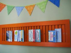 books are lined up on the orange shelf in front of the bookcase and bunting