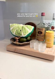 a wooden tray topped with bottles and glasses next to an elephant figurine on top of a counter