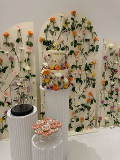 three white vases with flowers and cookies on them in front of a floral wall