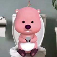 a small pink bear sitting on top of a toilet seat holding a cell phone in it's paws