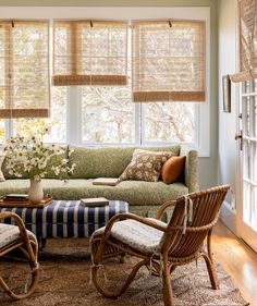 a living room filled with furniture and windows covered in shades of brown, white and blue