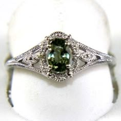 a green and white diamond ring sitting on top of a table