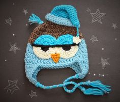 a crocheted blue and brown hat with an owl on it's face