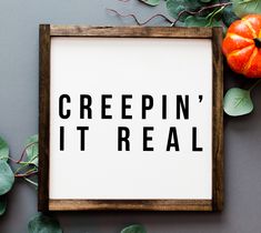 a framed sign that says creepin'it real next to some leaves and pumpkins