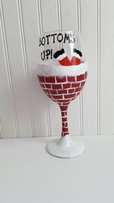 a red and white wine glass sitting on top of a table next to a wall