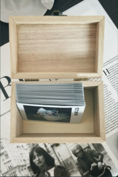 an open wooden box with photos in it on top of a table next to papers