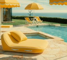 an inflatable chaise lounge next to a swimming pool with yellow umbrellas